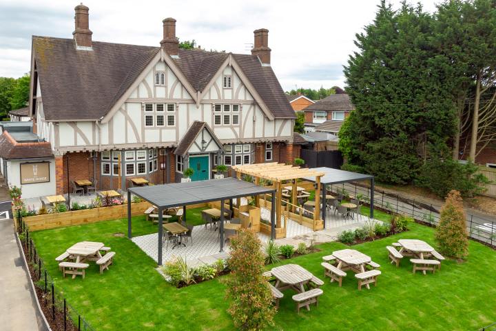 Beer garden with patio covered seating and uncovered grass areas.